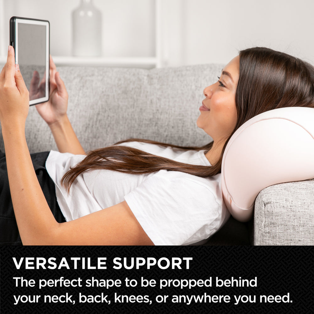 Woman using a neck pillow while sitting on a couch with a tablet.